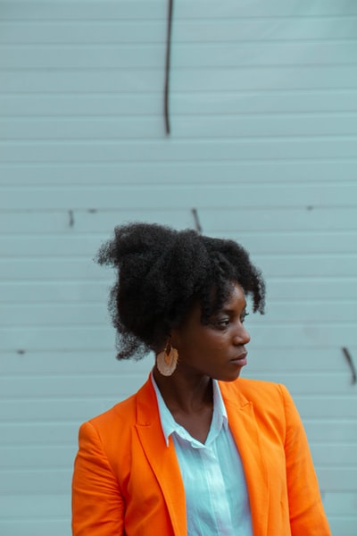 女人穿着橙色夹克站在白墙
